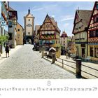"Rothenburg o.d. Tauber" steht unten links. Kopfsteinpflasterstraße mit bunten Fachwerkhäusern, Turm im Hintergrund.