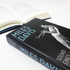 „MILES DAVIS SOUND EINES LEBENS“ steht groß auf einem geschlossenen Buch. Daneben liegt ein geöffnetes Buch.