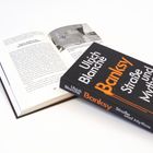 Zu sehen ist ein Buch mit dem Titel "Banksy: Straße und Mythos, Eine Biografie" von Ulrich Blanché. Es liegt aufgeschlagen da.