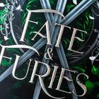 "Fate & Furies" ist in großen, metallisch schimmernden Buchstaben geschrieben. Im Hintergrund sind Schwerter und florale Muster.