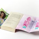 Ein offenes Buch zeigt eine Innenseite mit Text über Korallenstrand und eine bunte Illustration mit zwei Stiften. Links ein Foto einer Frau.