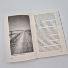Seite 168: "Kein Strauch, kein Baum, kein Schatten". Schwarz-Weiß-Foto eines langen, unbefestigten Weges durch eine karge Landschaft.