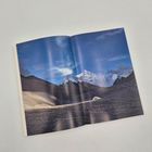 Keine erkennbaren Texte vorhanden. Eine Landschaft mit schneebedeckten Bergen unter blauem Himmel auf einer Buchseite.