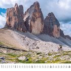 Kalenderseite mit August-Daten. Ein Radfahrer fährt in beeindruckender Berglandschaft mit felsigen Gipfeln.