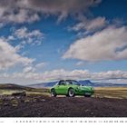 "Porsche 911 Targa". Grünes Auto vor einer weiten, hügeligen Landschaft mit Wolken und blauem Himmel.