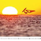 Kalenderblatt mit August-Daten. Ein Windsurfer in der Luft bei Sonnenuntergang über dem Meer.