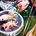 Text: "KOI – HAR GOW. Tipp: Die Kois sind ein absoluter Hingucker, aber...". Zwei Dumplings in Fischform auf einem Teller.