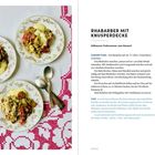 "Rhabarber mit Knusperdecke. Süßsauerer Frühsommer zum Dessert. Drei Teller mit Rhabarbercrumble auf gehäkeltem Tischtuch."
