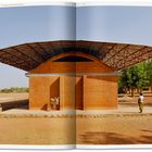 "Place — The Gando Projects — Primary School Extension" oben; Gebäude mit Ziegelfassade, markantes Dach, Esel und Mensch in der Szene.