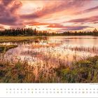 August, mit Kalender und See in Lappland bei Sonnenuntergang, umgeben von Bäumen und Gräsern, Himmel färbt sich rosa.
