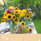 August mit einem Kalender und einem prächtigen Strauß aus Sonnenblumen und Sommerblumen auf einem Tisch im Garten.