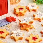 Text "Merry Xmas" auf einer Fußmatte, Weihnachtssterne mit roter Füllung, grüner Baumschmuck, rote Tür.