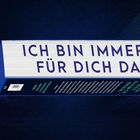 „ICH BIN IMMER FÜR DICH DA“ steht in großen Buchstaben auf einem Block vor einem dunklen, wolkigen Hintergrund.