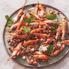 Babykarotten, Kichererbsen, Walnüsse, Joghurtsoße und Minzblätter auf einem runden, grauen Teller angerichtet.