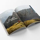 „Bergsport im 21. Jahrhundert“ und „Sind die Alpen noch zu retten?“ auf Buchseite vor Bergkulisse mit Hütte.