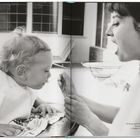Text: „At home with the Ferrers on his birthday, Sean tries cake for the first time — Audrey shows him how it is done.“
Rechts eine Frau mit offenem Mund, links ein Kind mit einem Löffel.
