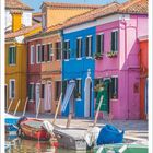 August, 1–31. Bunte Häuser und Boote entlang eines Kanals bei Sonnenschein.