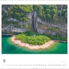Kalenderblatt August: Luftaufnahme einer grünen Insel vor einer Felswand mit Wasserfall am Seeufer, unten Monatsübersicht.