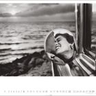 Text: USA, Berkeley, California, 1955. Schwarz-weißes Bild: Ein Paar küsst sich in einem Autospiegel, Meer im Hintergrund.