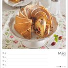 März, 11. Woche. Ein Gugelhupf mit Puderzucker auf einem Tortenteller. Eine Scheibe auf einem Teller daneben.