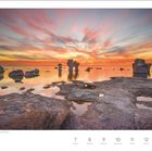 Juni-Kalenderblatt mit Wochentagen 7-13. Felsformationen im Meer bei Sonnenuntergang, orangefarbener Himmel.