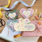 Viel Glück für dich. Alles Liebe für dich. Blumenmotive auf herzförmigen Karten, Geschenkverpackung mit Bändern.