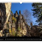 August. Bizarre Formationen in der Felsengasse im Bielatal. Kalender mit Landschaftsansicht: steile Felsen, Bäume, blauer Himmel.