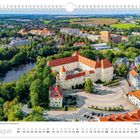 August; Schloss Freudenstein aus der Luftperspektive; Kalenderansicht; Gebäude mit roten Dächern umgeben von Bäumen und einem Teich.
