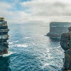 „Downpatrick Head, 5.49“. Steile Klippen am Meer, klare See, eine Person steht am Rand.
