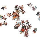 Es sind lose Puzzle-Teile mit bunten Mustern und Figuren auf einer weißen Oberfläche verteilt.