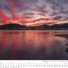 Siebengebirge – Blick über den Rhein zum Siebengebirge im Morgenrot. Ufer und ruhiges Wasser mit dramatischem Himmel.
