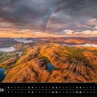 Text: „Norwegen 08“. Kalenderansicht August. Weitläufige, bergige Landschaft bei Sonnenuntergang mit Regenbogen.