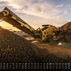 Kalender für September unten. Gelbe Industriemaschine befördert Steine. Geröllhaufen und Sonnenuntergang im Hintergrund.