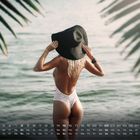 Kalender mit August-Daten, Frau im Badeanzug im Meer, umgeben von Palmenblättern.