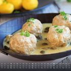 Ein Kalenderblatt mit Wochentagen und Zahlen. Ein Gericht mit vier Fleischklößen in einer cremigen Sauce, garniert mit Kräutern.