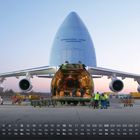 "INTERNATIONAL CARGO TRANSPORTER" steht auf einem großen Frachtflugzeug. Menschen laden Güter bei Sonnenuntergang ein. Kalender darunter.