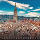 Text: „Bern 8“, Monatskalender, Stadt mit Münster, Herbstlaub, Berge im Hintergrund, blauer Himmel mit Wolken.