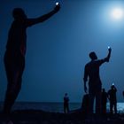 John Stanmeyer, 2013. Migranten suchen Mobilfunksignal. Silhouetten halten Handys in den Nachthimmel über dem Meer.