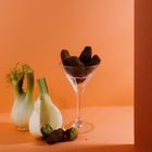 Ein Fenchel, Falafel in einem Cocktailglas, alles vor einem orangefarbenen Hintergrund.