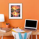 Ein Schreibtisch mit Laptop, Buch, Lampe und Stiften. An der Wand hängt ein Bild mit Flamingos in einem farbenfrohen Sonnenuntergang.