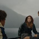 Keine erkennbaren Texte. Drei Menschen in Regenkleidung auf einem Boot. Es ist bewölkt und die Stimmung ist angespannt.