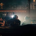 „P“ auf einem Schild. Soldaten in einem Schlauchboot, beleuchtet von Scheinwerfern, unter einer Brücke mit Fahrrädern.