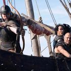 Krieger auf einem Schiff, einer spannt einen Bogen, andere halten Ruder; alle tragen Rüstungen und Helme.