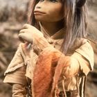 Eine Puppe mit großen Augen, langen Haaren und spitzen Ohren trägt ein detailliertes, mittelalterliches Gewand.