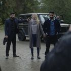 Zwei Männer halten eine Frau vor einem Geländewagen fest. Ein Mann zielt mit einer Pistole auf die Frau. Wald im Hintergrund.