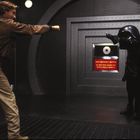 "SELF-DESTRUCT BUTTON. DO NOT PUSH UNLESS YOU REALLY, REALLY MEAN IT!" Zwei Personen zielen mit Fingern aufeinander.