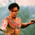 Ich kann keine Texte im Bild erkennen. Ein muskulöser Mann mit Tattoos hält ein Messer in einer kampfbereiten Pose.