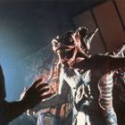 Zwei Figuren agieren in einem dunklen Raum. Eine davon ist ein monströser Dämon mit Hörnern und Krallen.