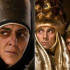 Links Person in dunklem Gewand und Hut, skeptisch blickend. Rechts zwei in aufwendigen Pelz- und Goldkleidungen, besorgt.
