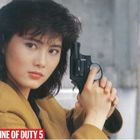 IN THE LINE OF DUTY 5. Frau mit dunklem Haar hält eine Pistole, schaut entschlossen, trägt gelben Blazer.